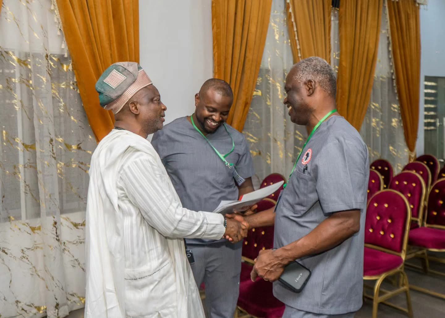 A community leader greets two outreach team members inside a hall.