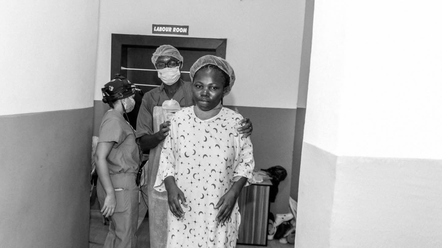 A patient stands with clinical staff outside the labour room.