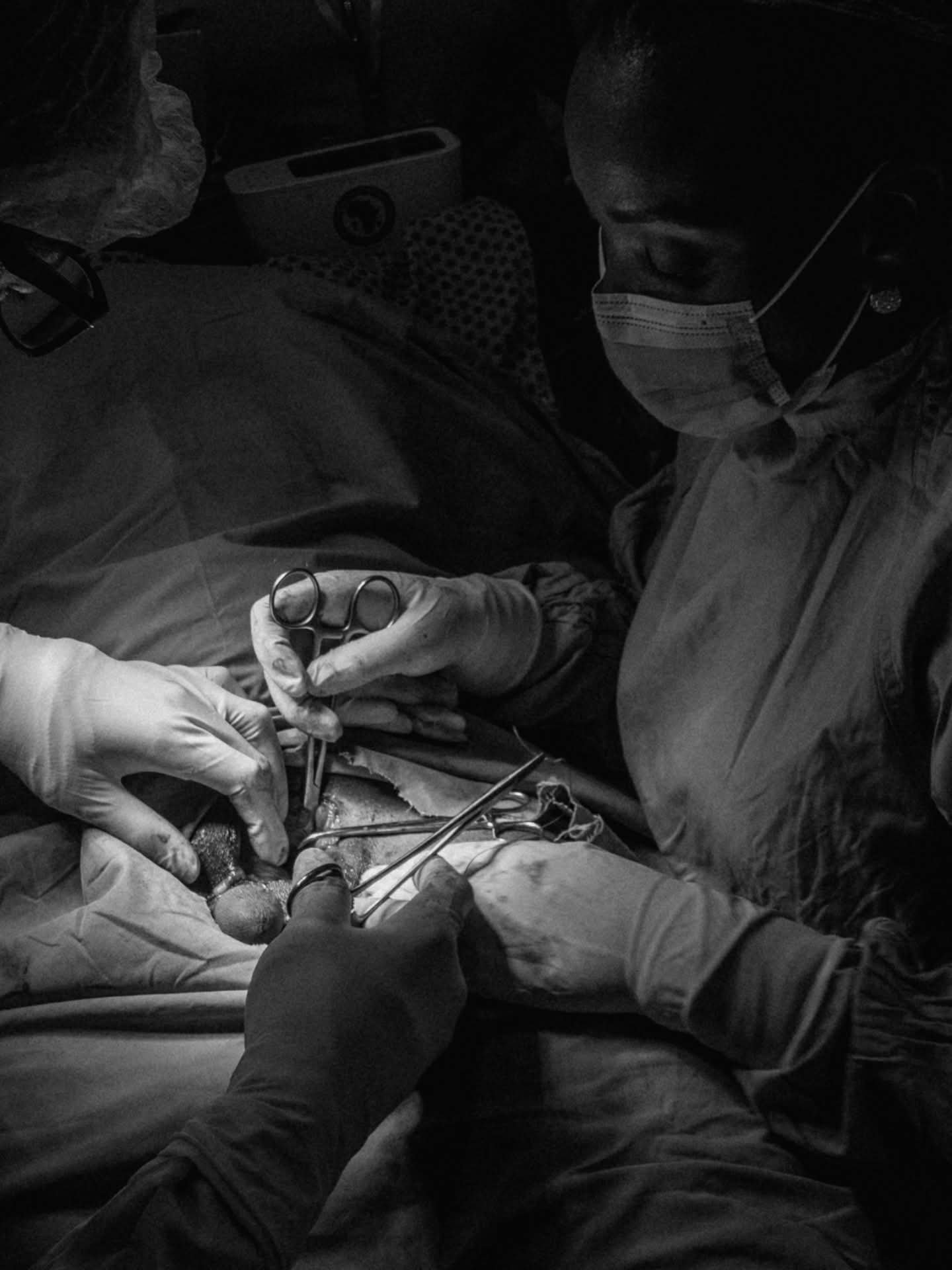 Surgeons in protective clothing perform a medical procedure.
