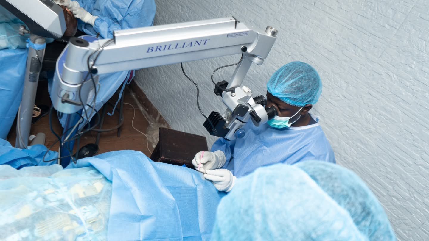 A surgical team member works with an operating microscope during the UBOMI outreach.