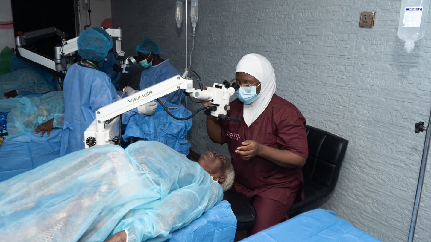 An eye care clinician examines a patient with an ophthalmic microscope.